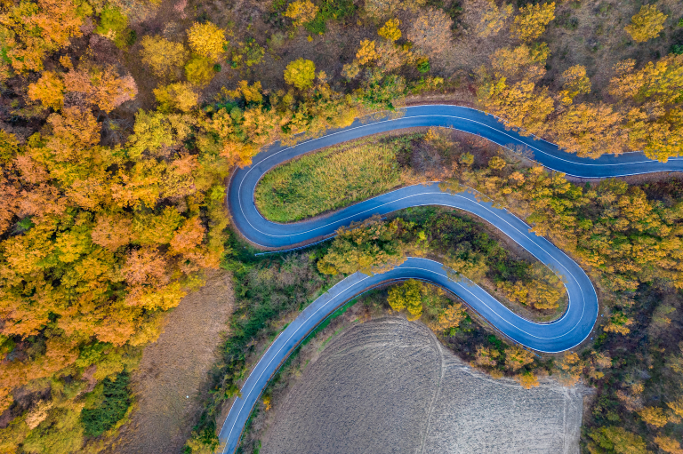 aerial-view-of-a-curved-road-winding-through-an-au-2024-03-08-00-34-12-utc