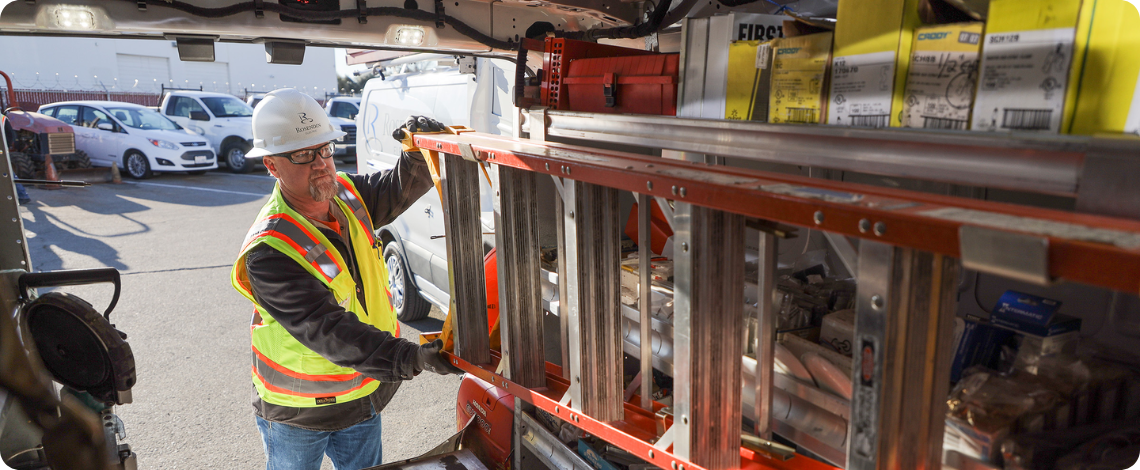 electrician loading a ladder into a service van